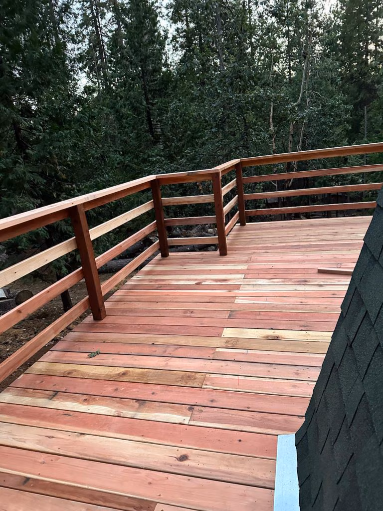 Wood deck with custom horizontal-rail wood railing overlooking a wooded hillside.